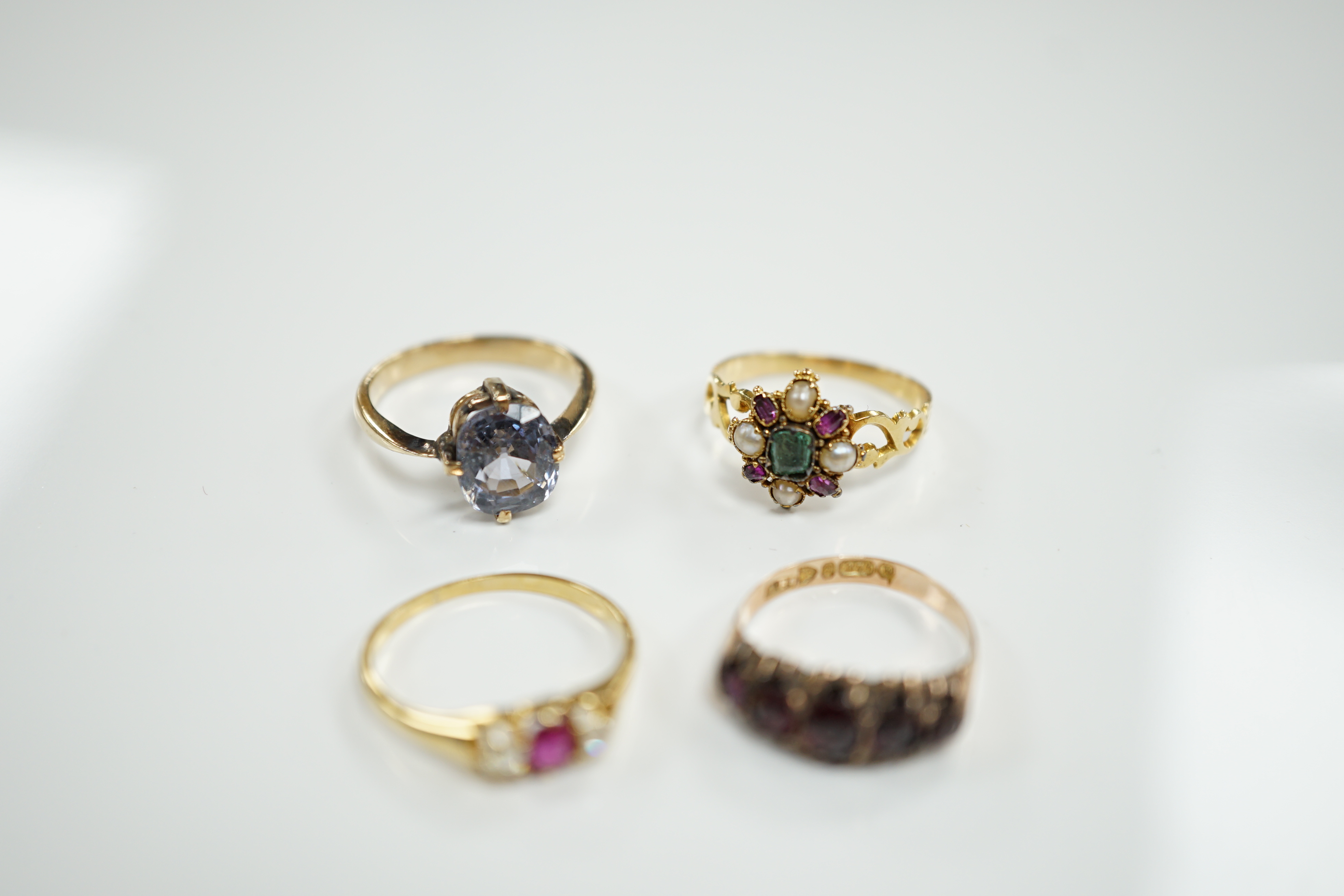 A late Victorian yellow metal, emerald, garnet and split pearl cluster set ring, in the Suffragette colours, size M/N and three other rings including Victorian 9ct gold and garnet set half hoop and 18ct, ruby and diamond